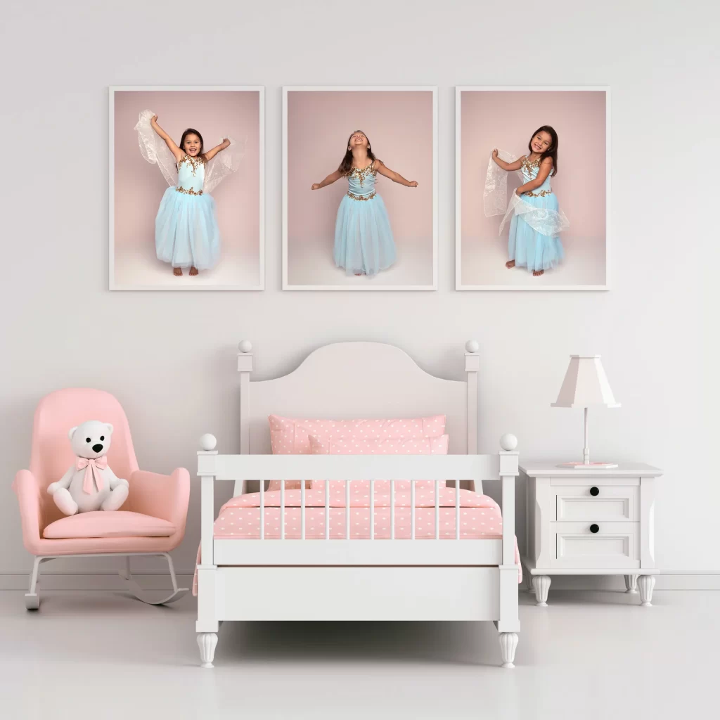 Framed triptych of a young girl dancing in a blue costume displayed above a white bed in a pink and white girls' bedroom