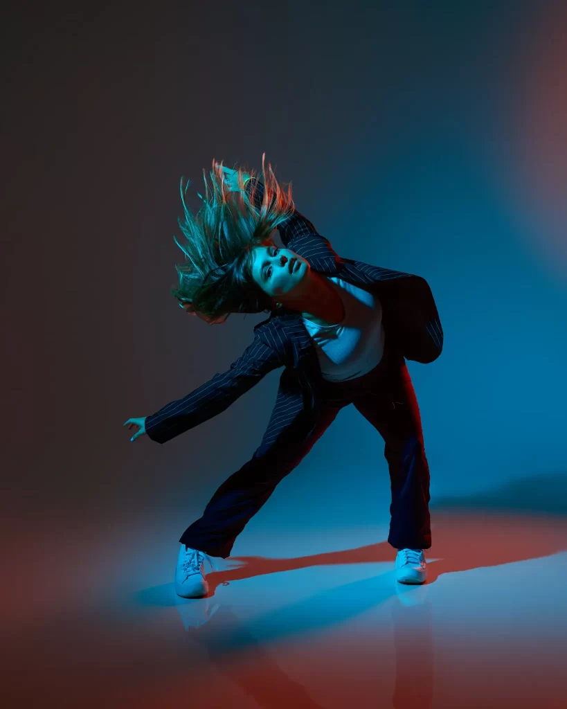 Dancer in motion under vivid red and blue neon lighting with dramatic hair movement