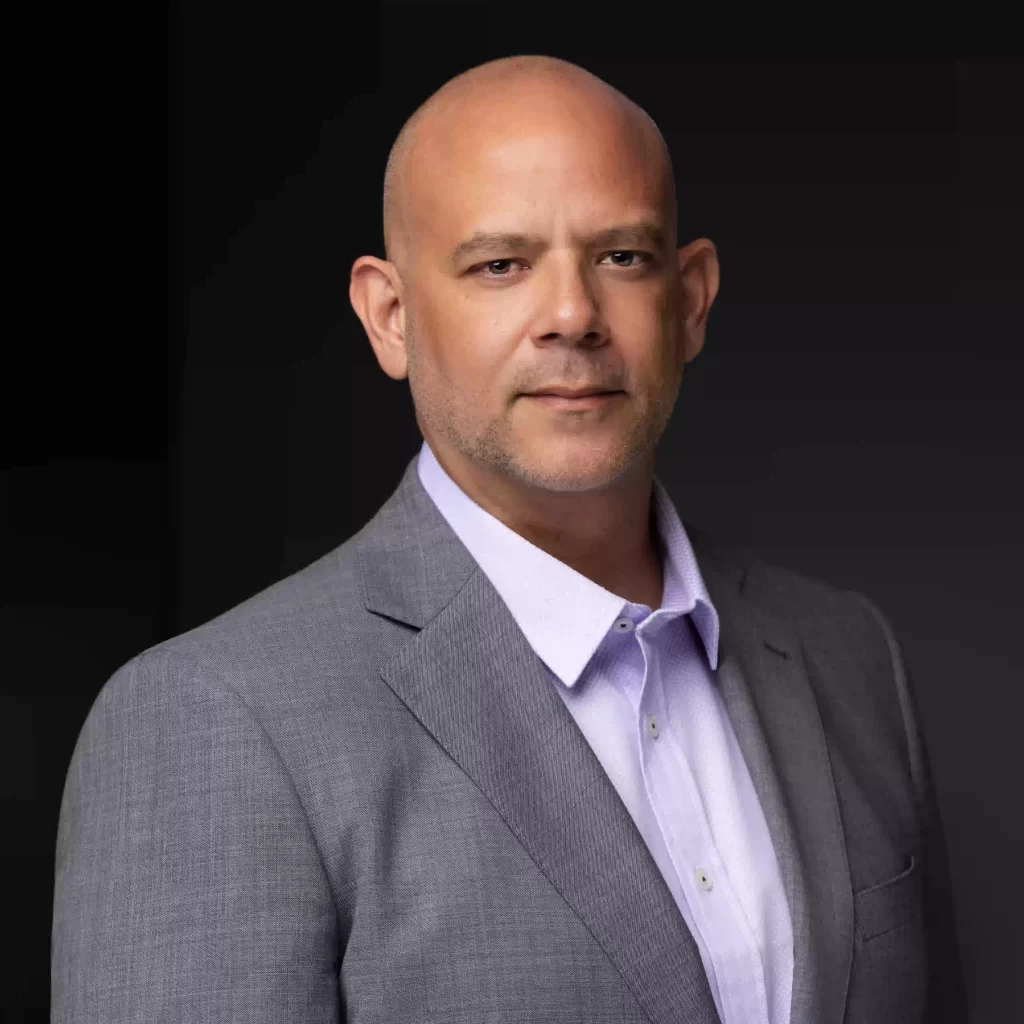 Professional headshot of man in grey suit on a black background, photographed in Ocala.