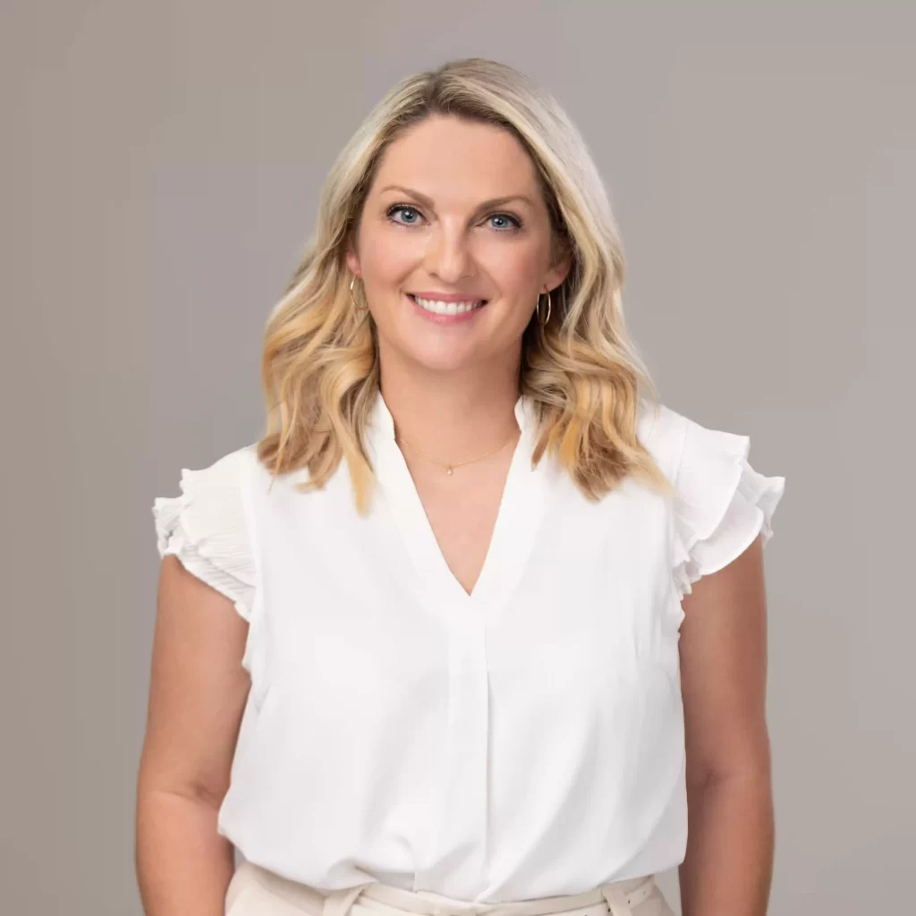 Professional headshot of woman in white blouse on a grey background, photographed in Ocala.